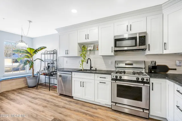 a kitchen with stainless steel appliances granite countertop a stove top oven a sink a counter space and cabinets