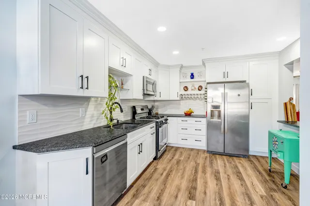 a kitchen with white cabinets sink and stainless steel appliances