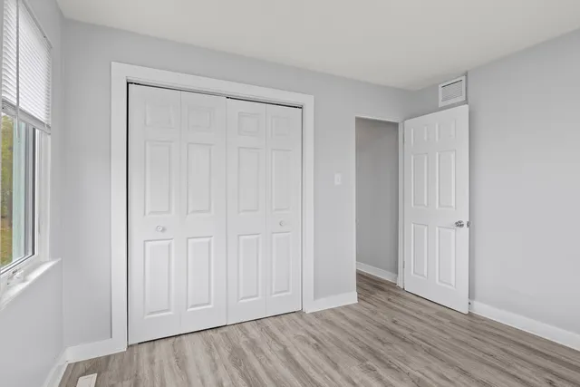 an empty room with wooden floor and windows