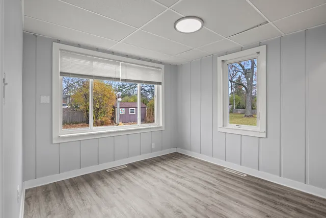 an empty room with wooden floor and windows