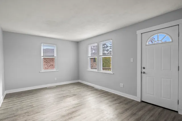 a view of an empty room with window and wooden floor