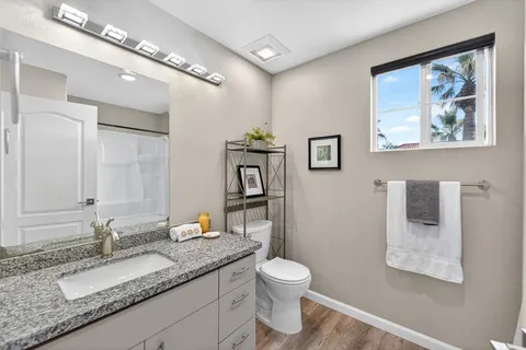 a bathroom with a granite countertop sink a toilet and a mirror