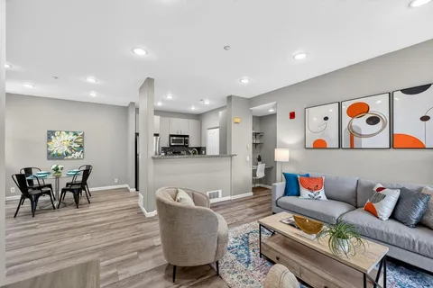 a living room with furniture and a dining table with wooden floor
