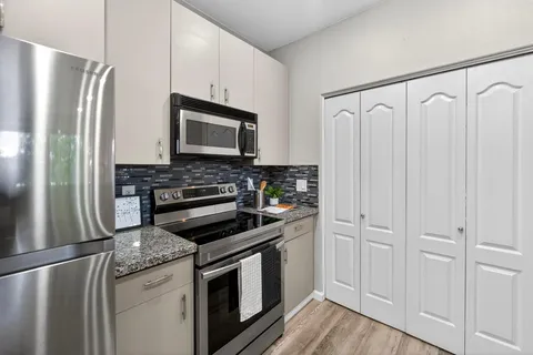 a kitchen with granite countertop a refrigerator stove and microwave
