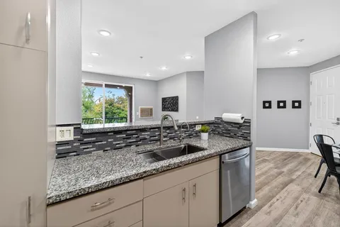 a kitchen with granite countertop a sink and a white wooden cabinets