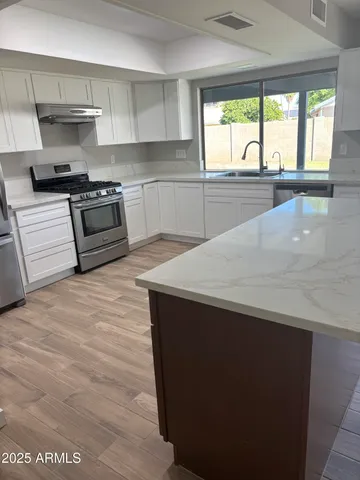 a kitchen with stainless steel appliances granite countertop a stove a sink and a refrigerator