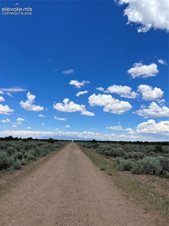 Lot 8 Melby Ranch Road San Luis, CO 81152 - Photo 1 of 20 Expansive gravel road extending into the horizon, flanked by natural shrubland vegetation