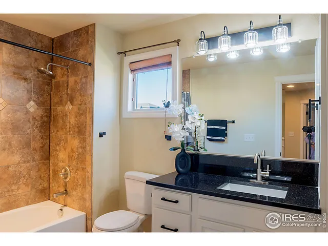 a bathroom with a granite countertop sink a mirror and shower