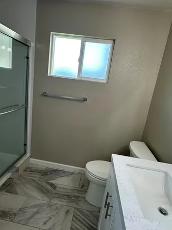 a white toilet sitting next to a bathroom sink and vanity