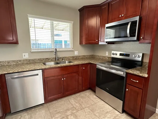 a kitchen with granite countertop cabinets stainless steel appliances a sink and a window