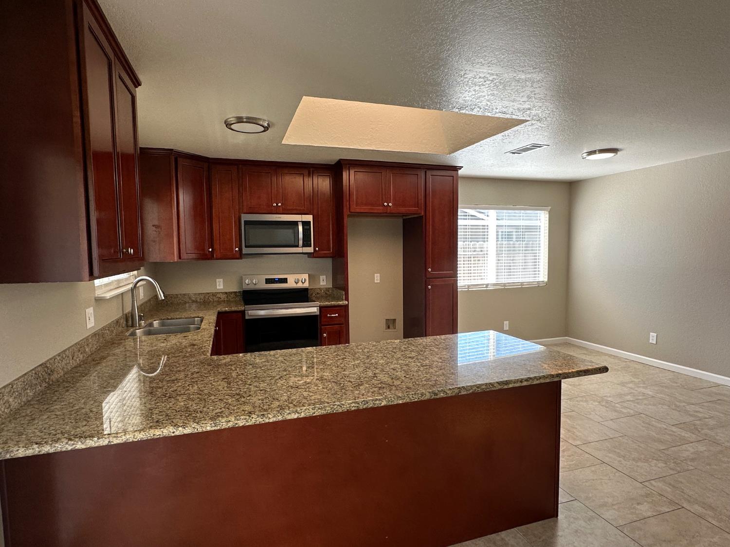 924 Kingery Drive Ripon, CA 95366 - Photo 6 of 18 a kitchen with granite countertop stainless steel appliances a sink a stove top oven a counter space and cabinets