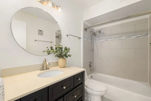a bathroom with a granite countertop sink a toilet and shower