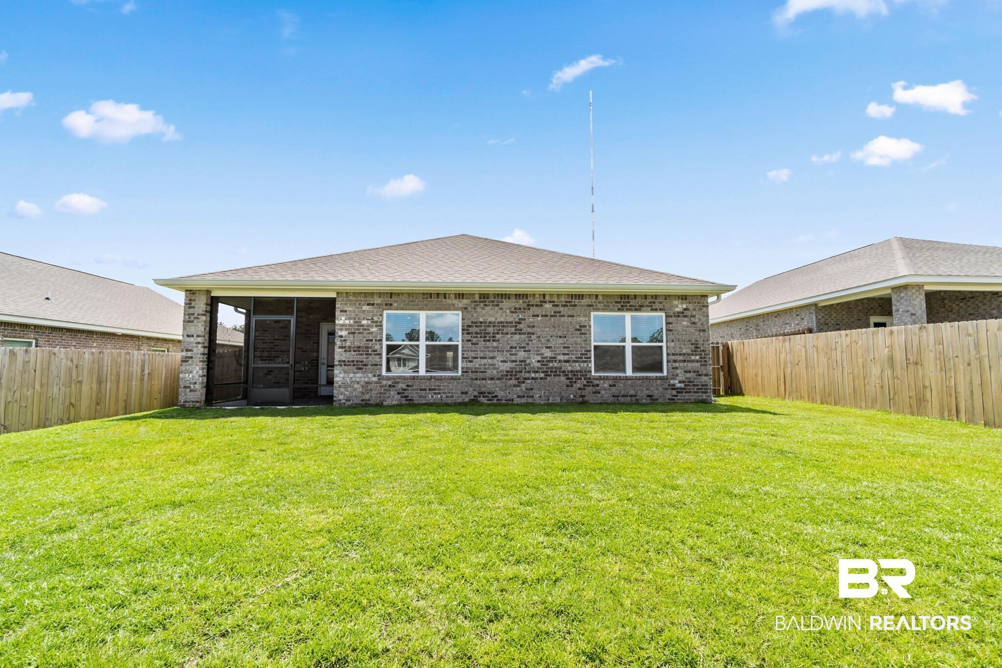 32125 Lyon Road Daphne, AL 36527 - Photo 38 of 70 Expansive green lawn with a brick exterior home featuring a screened-in porch, multiple windows, and a shingled roof
