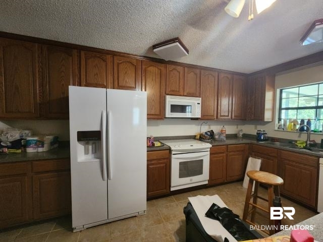 32749 Antietam Road Lillian, AL 36549 - Photo 7 of 47 Kitchen featuring light tile patterned floors, white appliances, sink, ceiling fan, and a textured ceiling