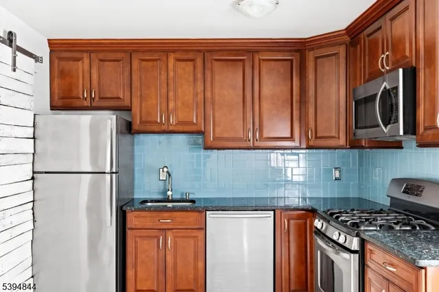 a kitchen with stainless steel appliances granite countertop a refrigerator stove top oven and granite countertops with wooden floor