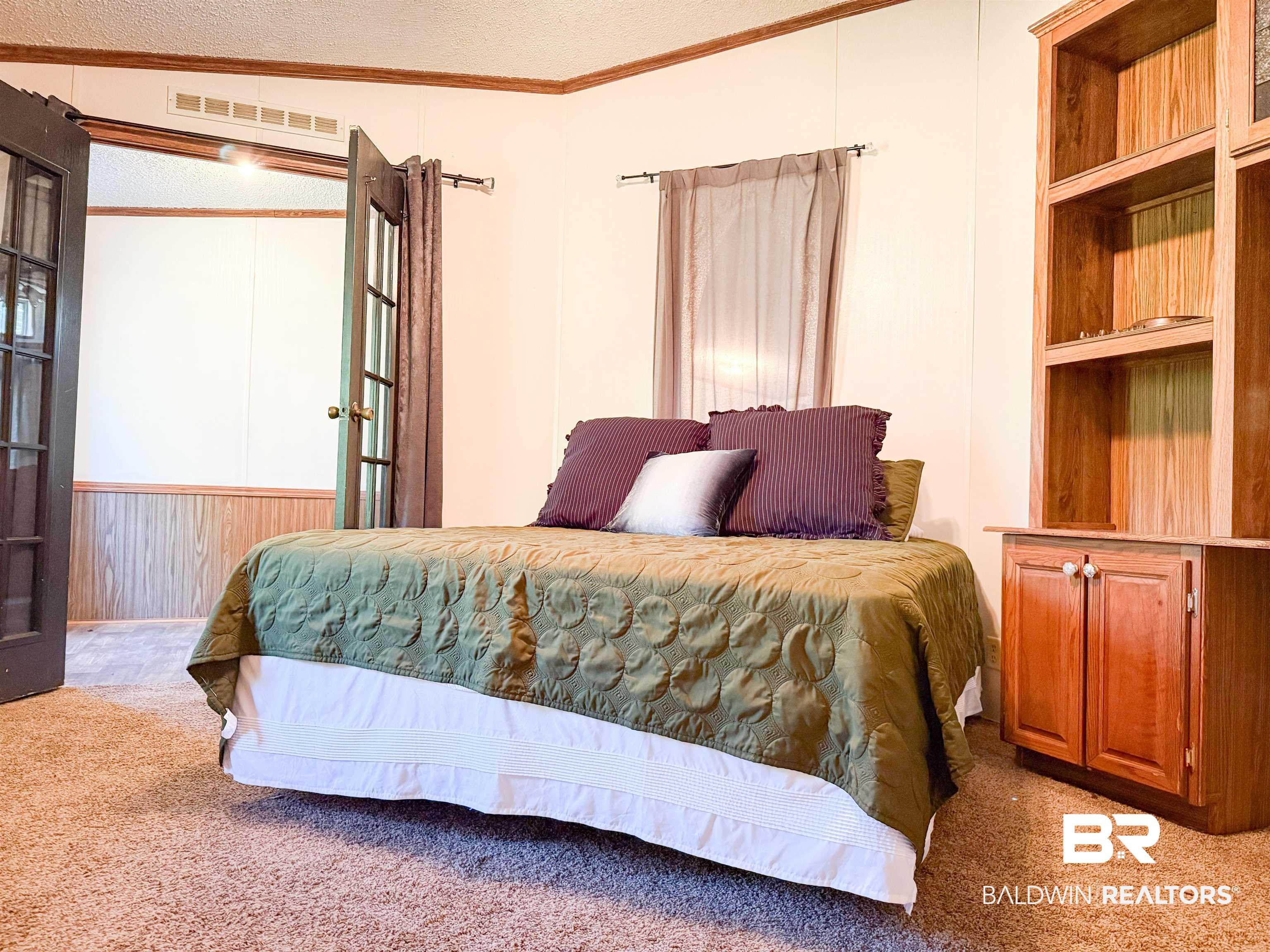3346 Hoomesville Road Brewton, AL 36426 - Photo 14 of 16 Bedroom with crown molding, a textured ceiling, carpet flooring, wooden walls, and french doors