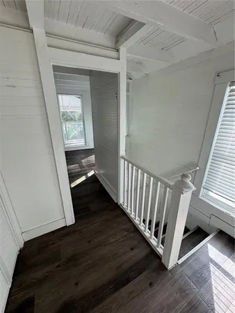 a view of a hallway to an empty room with wooden floor and stairs