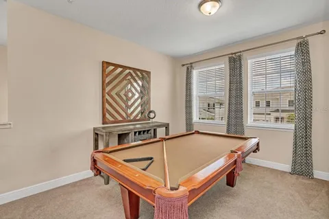 a living room with furniture pool table and windows