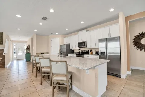 a kitchen with stainless steel appliances granite countertop a table chairs and a refrigerator