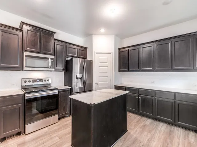 a kitchen with stainless steel appliances granite countertop a stove top oven microwave and refrigerator