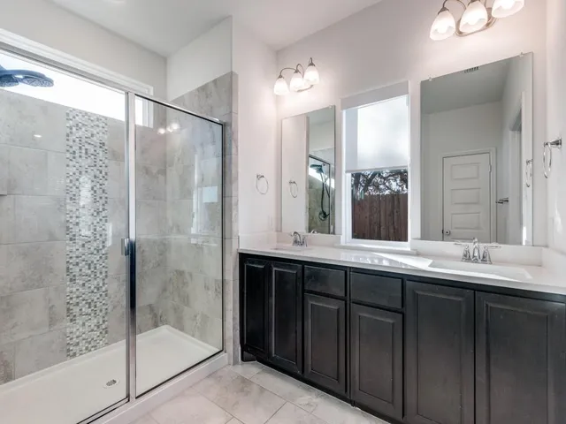 a bathroom with a double vanity sink mirror and shower