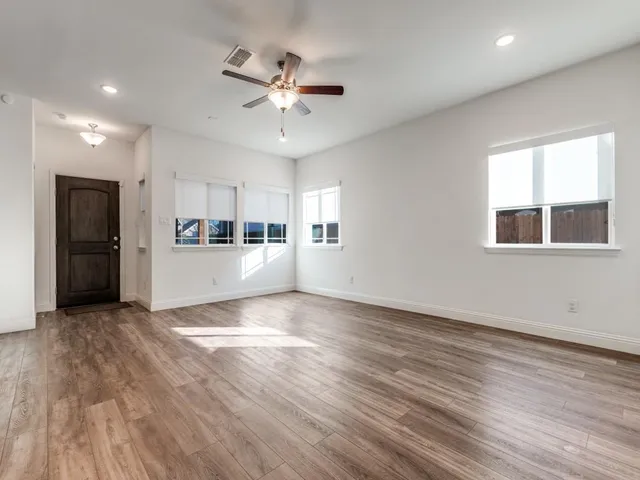 a view of an empty room with a window and wooden floor