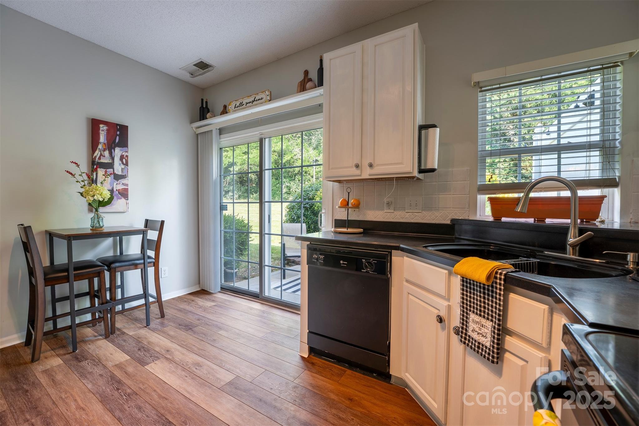 3412 Summerfield Ridge Lane Matthews, NC 28105 - Photo 10 of 30 a kitchen with granite countertop a stove top oven a sink dishwasher white cabinets and a dining table with wooden floor