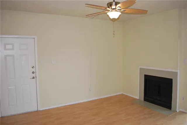 an empty room with a ceiling fan and a fireplace