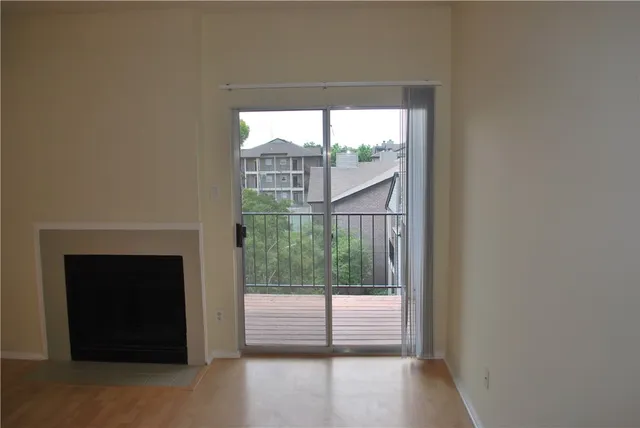 a view of empty room with wooden floor and fireplace