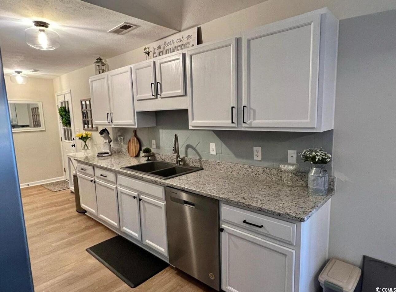 232 Oak Lea Drive Conway, SC 29526 - Photo 6 of 16 Kitchen featuring light stone countertops, stainless steel dishwasher, light wood-type flooring, a textured ceiling, and white cabinetry