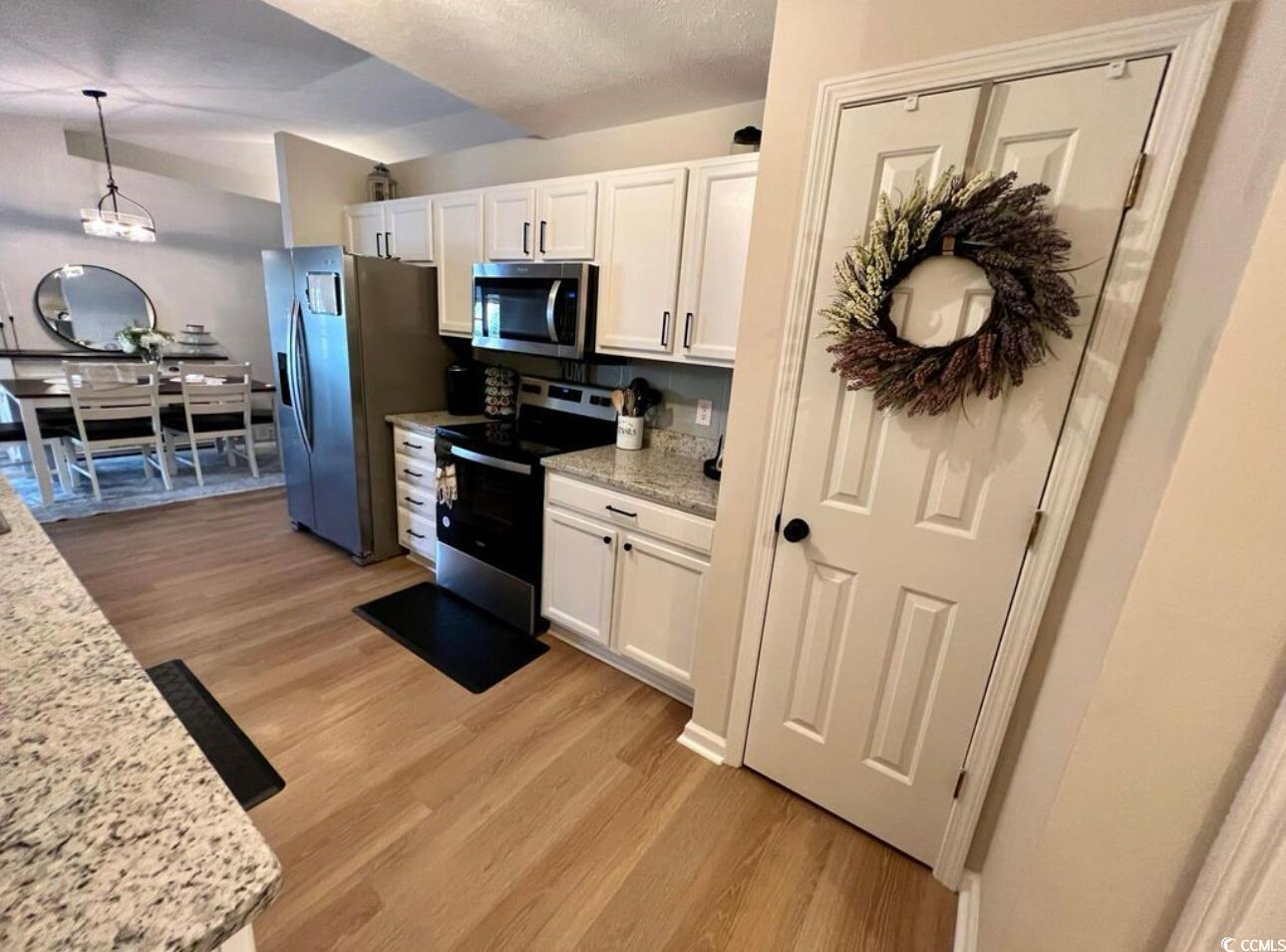 232 Oak Lea Drive Conway, SC 29526 - Photo 7 of 16 Kitchen featuring light stone counters, stainless steel appliances, white cabinetry, light wood-style flooring, and decorative light fixtures