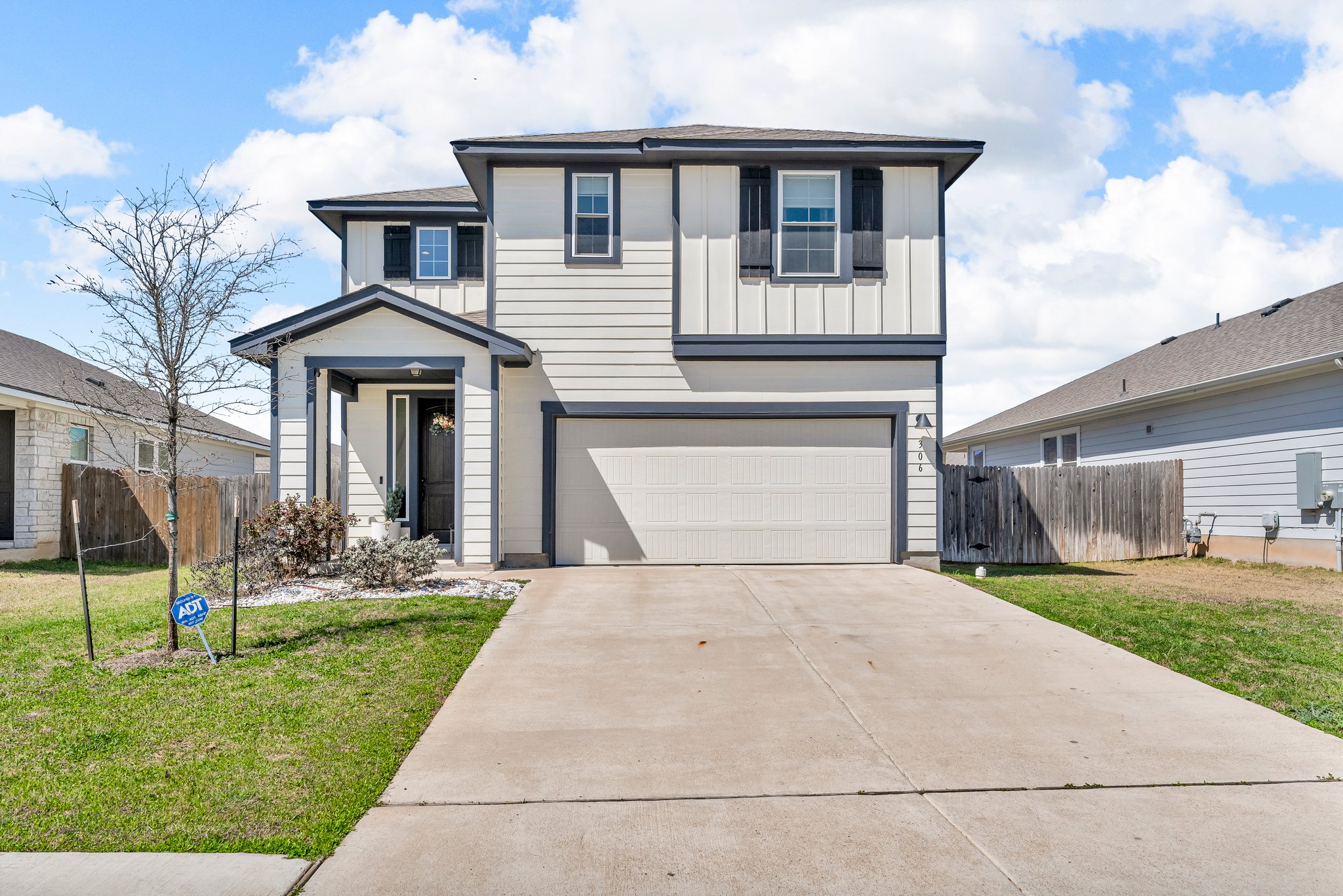 Traditional home featuring an attached garage, fence, board and batten siding, and driveway