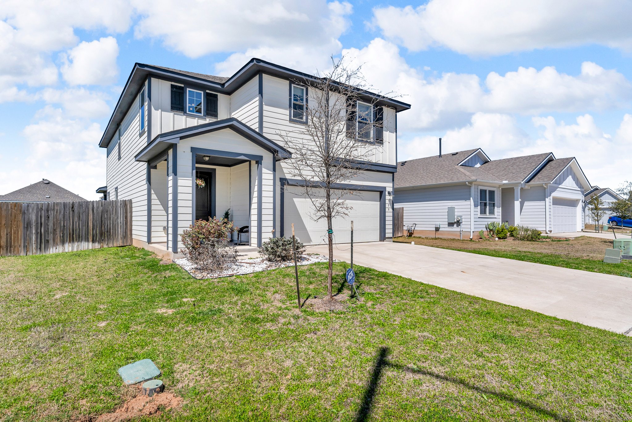 306 Cold Spg Loop Bastrop, TX 78602 - Photo 2 of 25 Traditional home with fence, driveway, a front lawn, a garage, and board and batten siding
