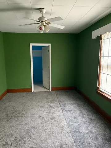 an empty room with windows and fan