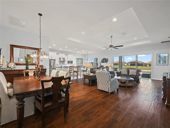 a living room with furniture kitchen view and a wooden floor