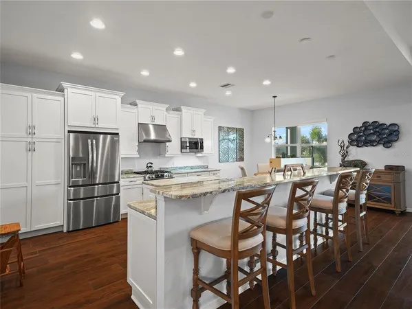 a living room with stainless steel appliances kitchen island granite countertop furniture wooden floor and a kitchen view