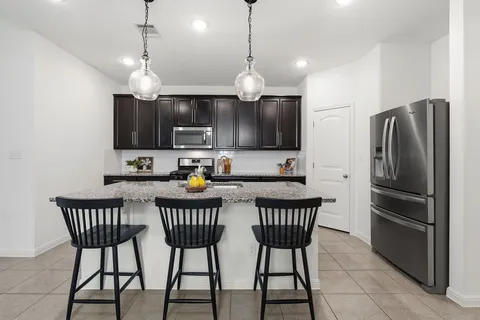 a kitchen with stainless steel appliances a dining table chairs refrigerator and microwave
