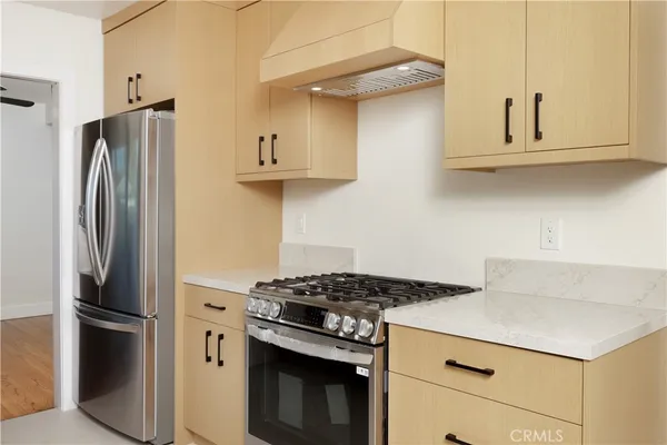 a kitchen with stainless steel appliances a refrigerator a stove and white cabinets