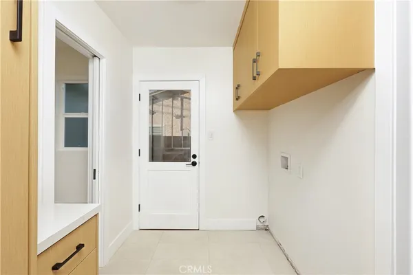 a view of a hallway with white cabinets and wooden floor
