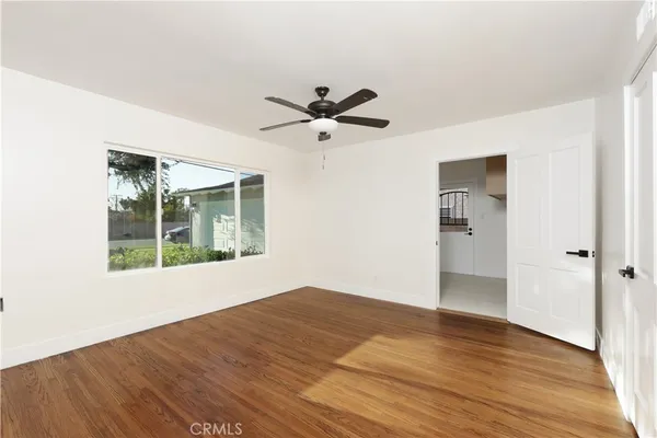 a view of empty room with wooden floor and fan