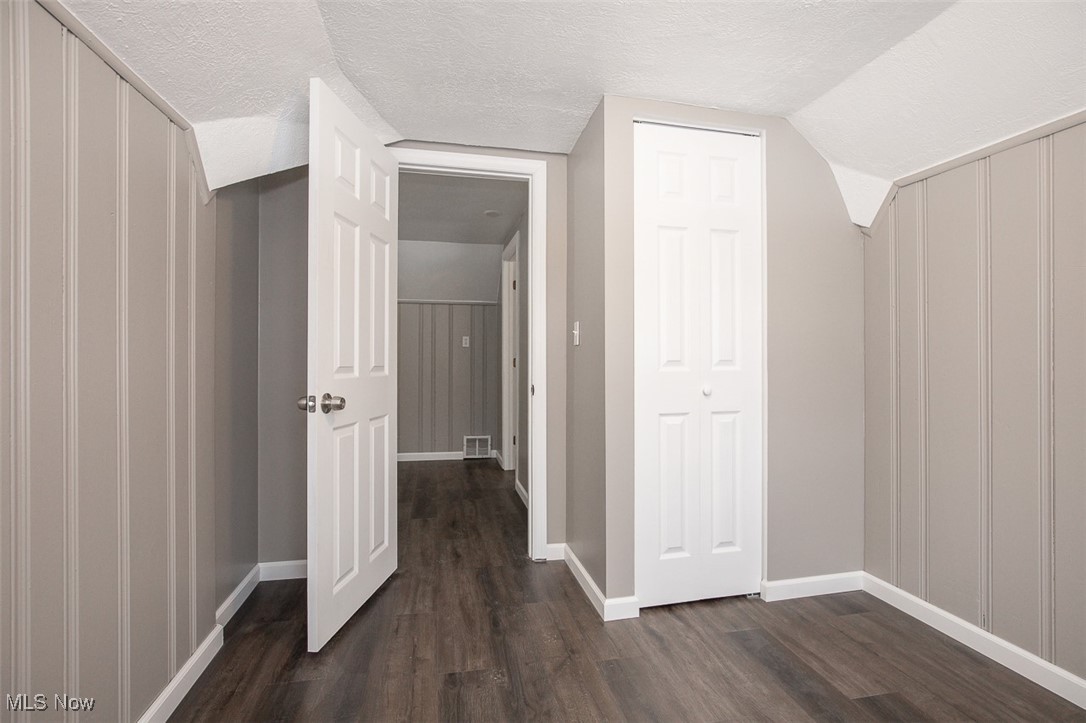 12328 Granger Road Cleveland, OH 44125 - Photo 28 of 37 Additional living space featuring dark wood finished floors, a textured ceiling, vaulted ceiling, and a decorative wall