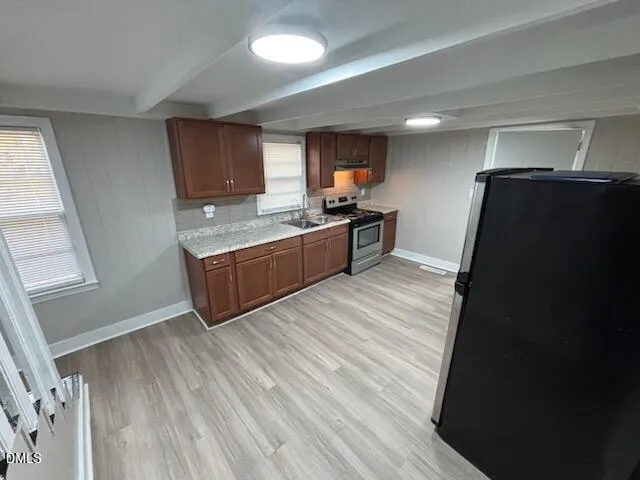 a kitchen with stainless steel appliances granite countertop a refrigerator and a stove top oven