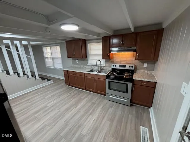 a kitchen with stainless steel appliances a stove a sink and white cabinets