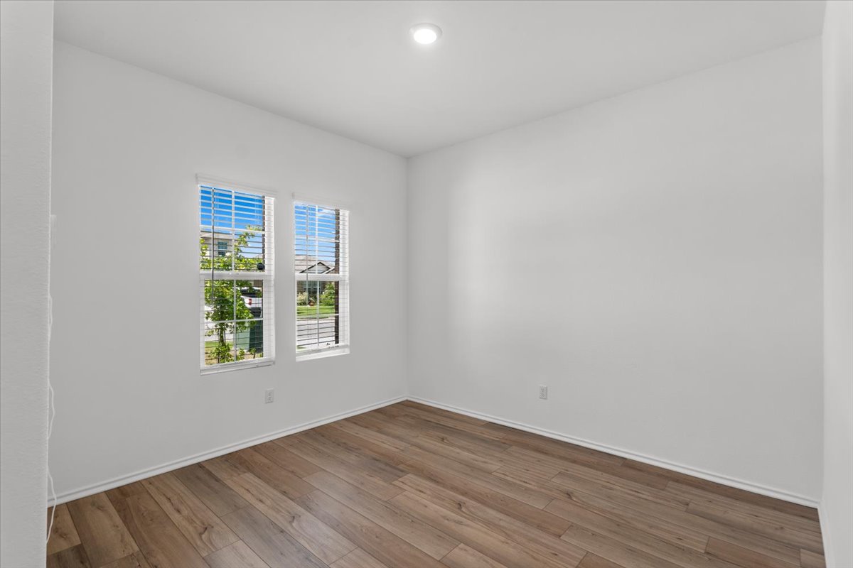 448 Perfect World Loop Jarrell, TX 76537 - Photo 20 of 40 Well-lit room featuring warm wood flooring and bright windows.