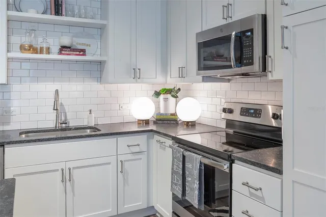 a kitchen with stainless steel appliances granite countertop a sink a stove and refrigerator