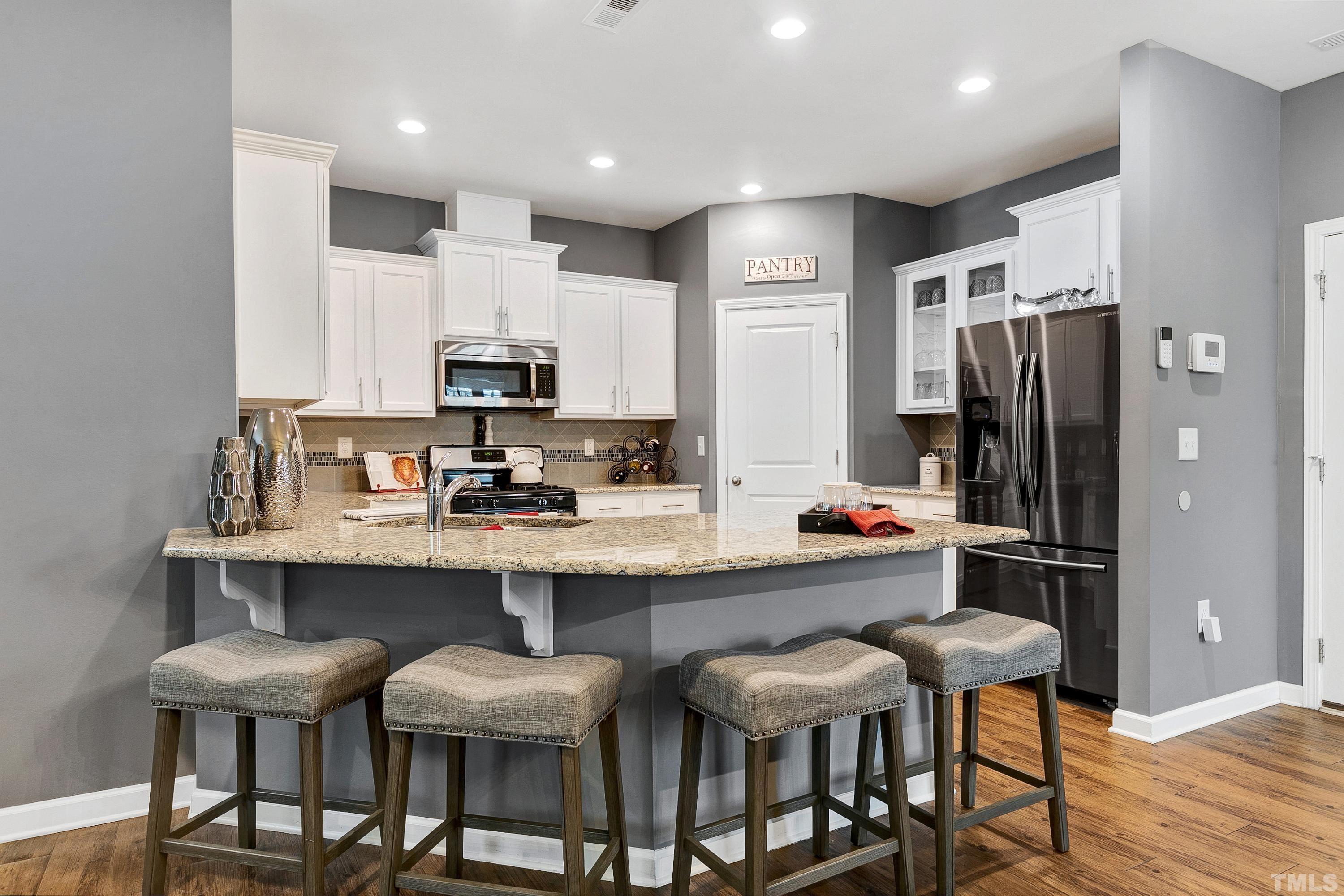 1161 Lookout Ridge Road Apex, NC 27502 - Photo 12 of 36 a kitchen with stainless steel appliances a table chairs refrigerator and microwave