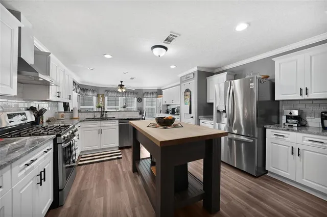 a kitchen with a sink stainless steel appliances and white cabinets