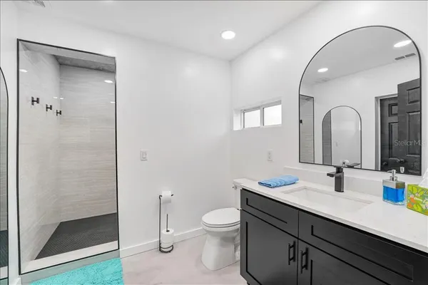 a bathroom with a granite countertop sink a toilet and a mirror