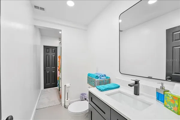 a bathroom with a granite countertop sink vanity mirror and toilet