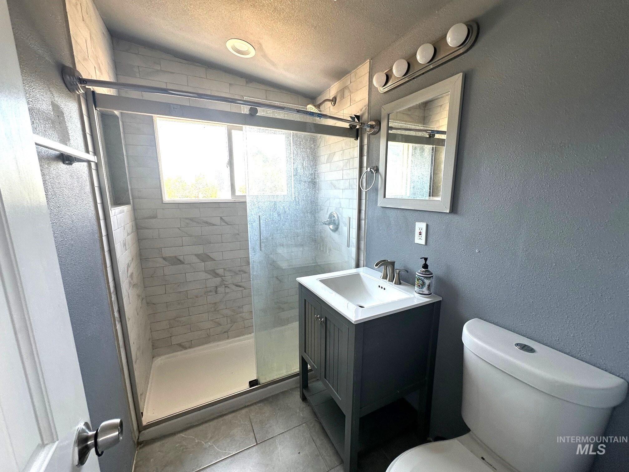 787 Southwest 3rd Street Ontario, OR 97914 - Photo 16 of 22 Full bath featuring a textured ceiling, a textured wall, a stall shower, vanity, and lofted ceiling